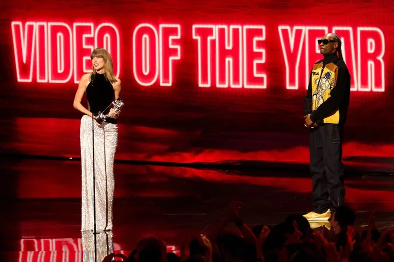 Taylor Swift and Snoop Dogg are standing on stage at the 2026 MTV VMAs