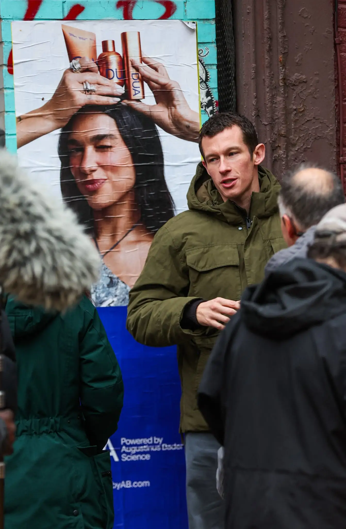 Callum Turner can be seen posing next to a poster of Dua Lipa while on the set of his new film One Night Only this afternoon in New York City