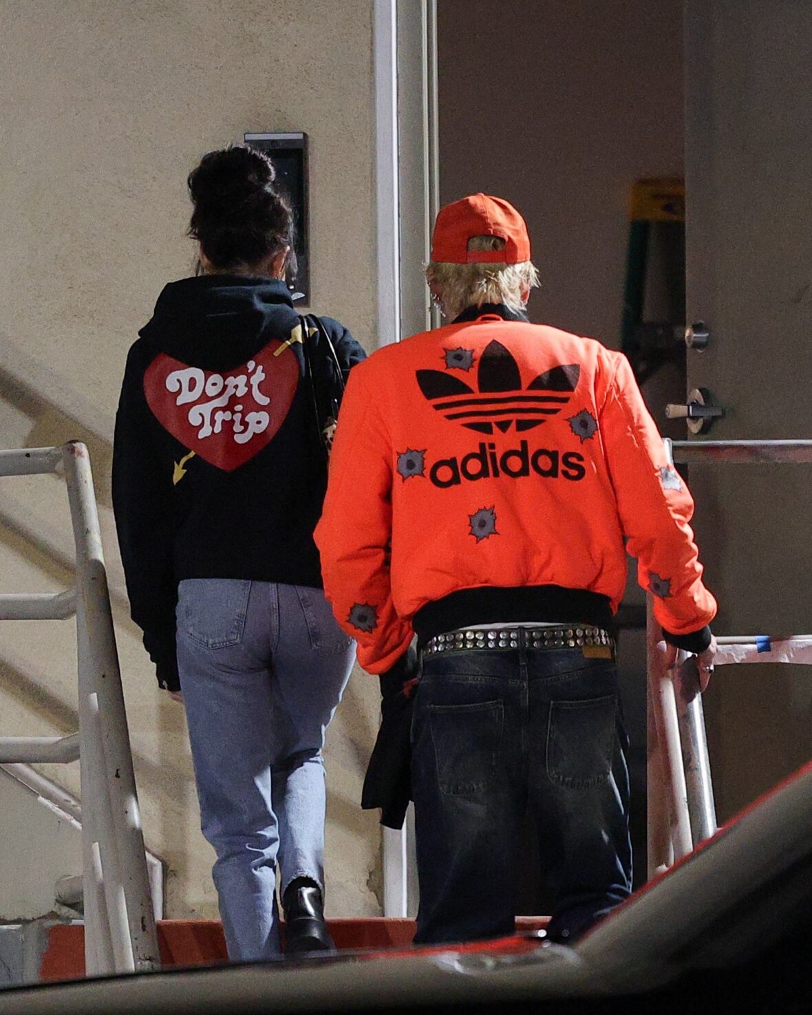 Dakota Johnson and Machine Gun Kelly seen at the studio on October 27, 2027 in Los Angeles, with their backs to the camera walking up the stairs