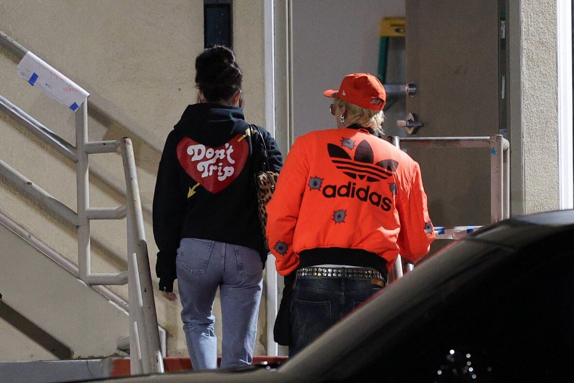 Dakota Johnson and Machine Gun Kelly seen at the studio on October 27, 2027 in Los Angeles, with their backs to the camera walking up the stairs