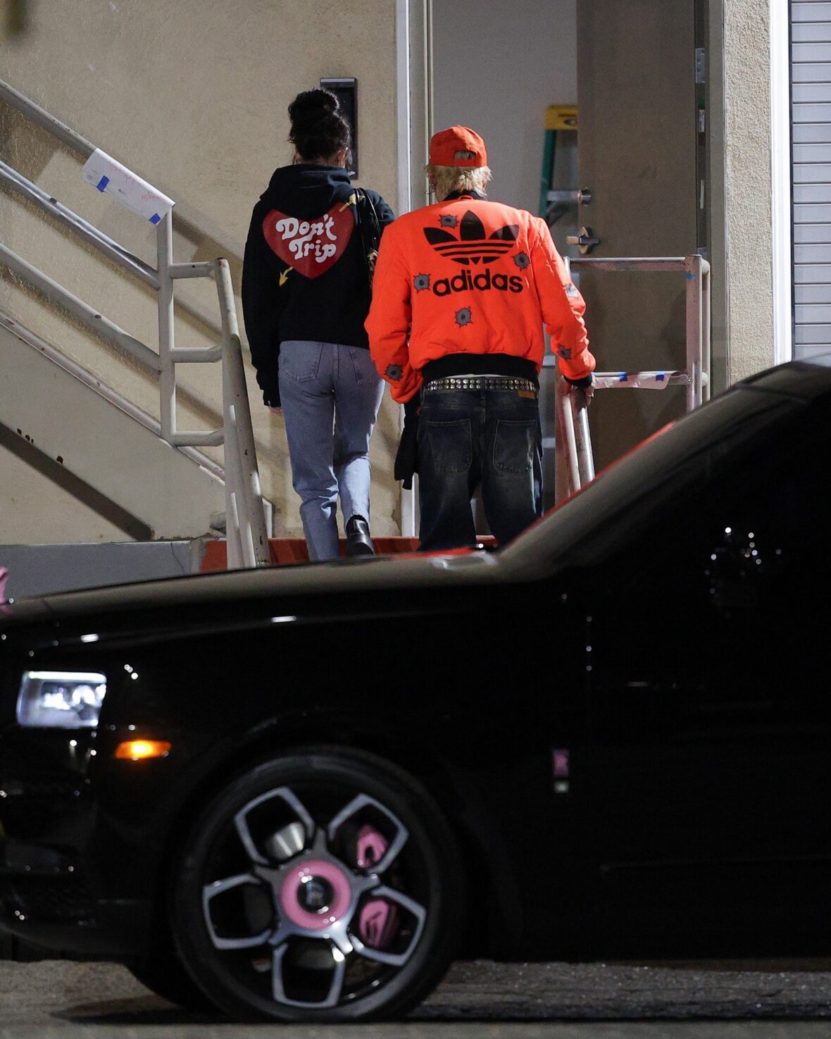 Dakota Johnson and Machine Gun Kelly seen at the studio on October 27, 2027 in Los Angeles, with their backs to the camera walking up the stairs