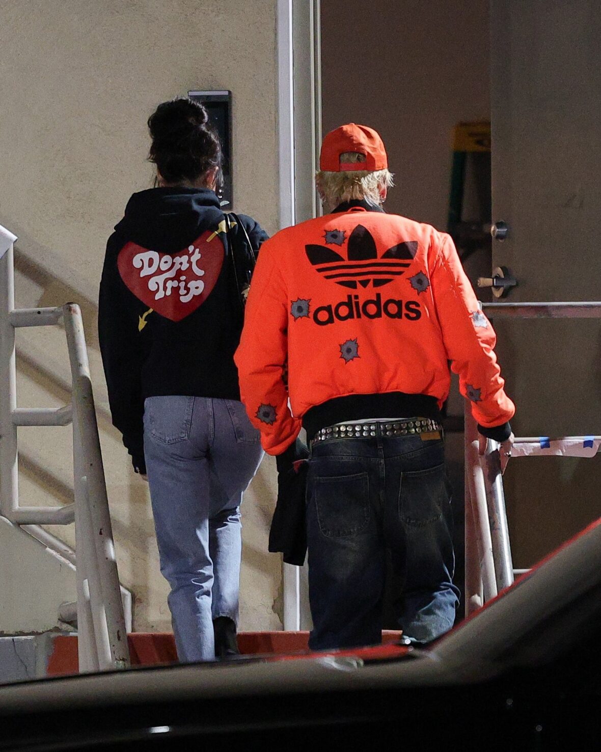 Dakota Johnson and Machine Gun Kelly seen at the studio on October 27, 2027 in Los Angeles, with their backs to the camera walking up the stairs