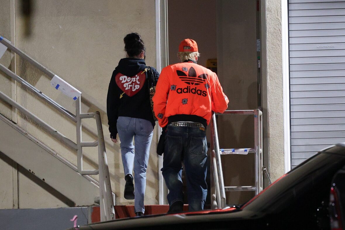 Dakota Johnson and Machine Gun Kelly seen at the studio on October 27, 2027 in Los Angeles, with their backs to the camera walking up the stairs