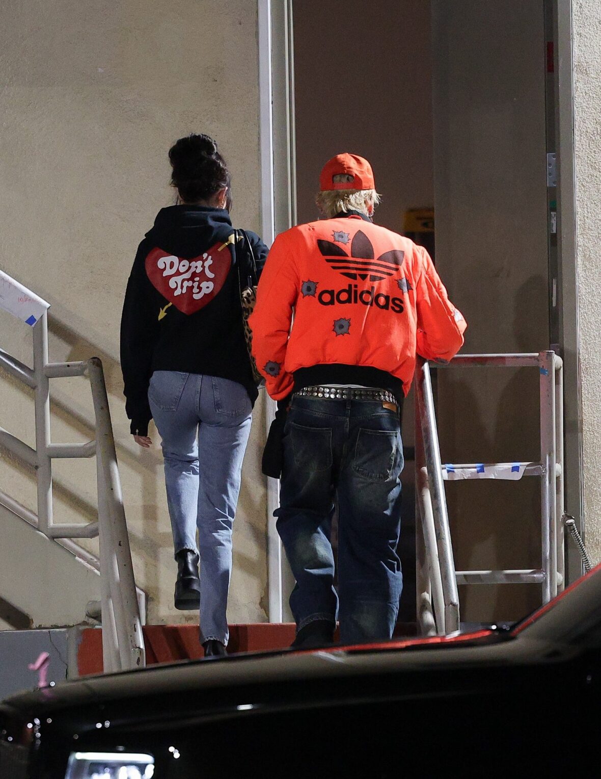 Dakota Johnson and Machine Gun Kelly seen at the studio on October 27, 2027 in Los Angeles, with their backs to the camera walking up the stairs