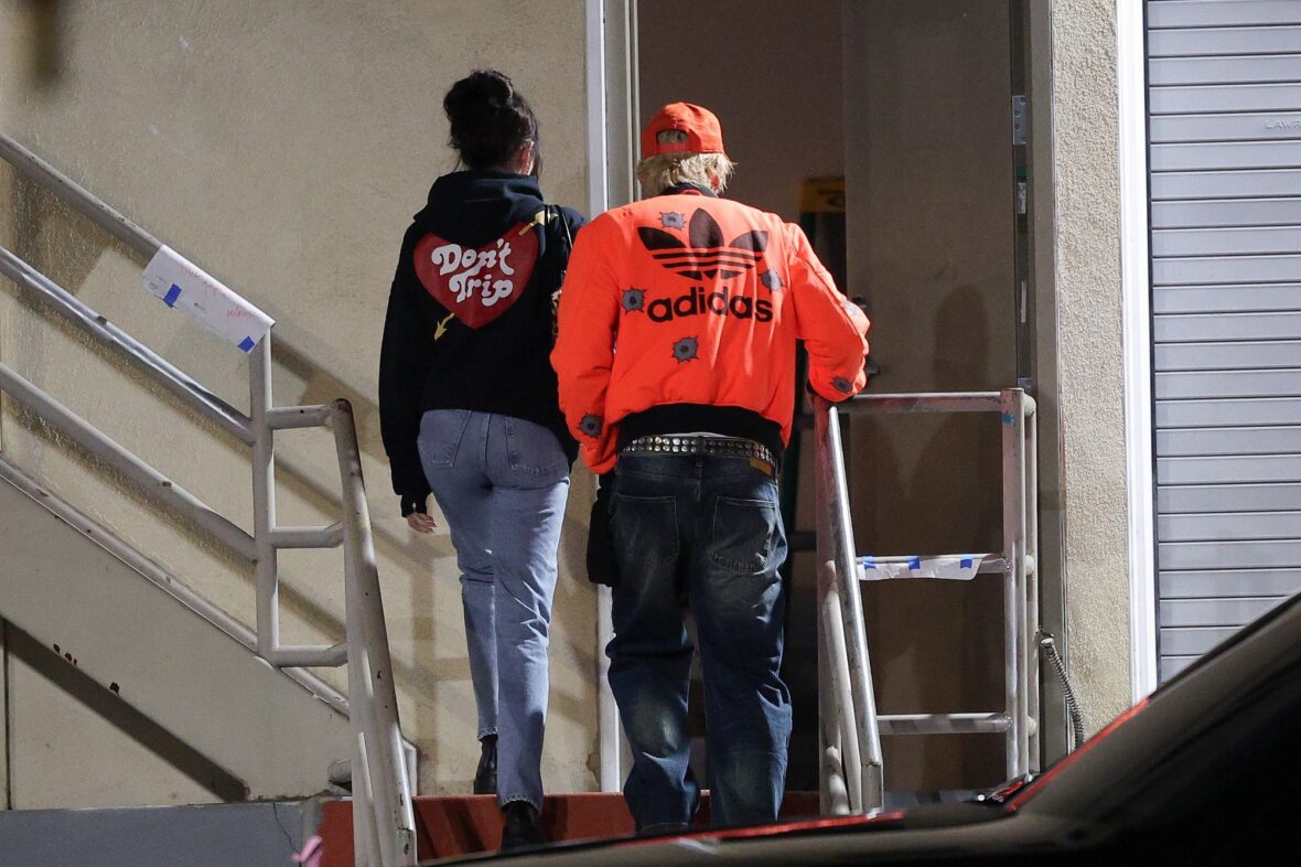 Dakota Johnson and Machine Gun Kelly seen at the studio on October 27, 2027 in Los Angeles, with their backs to the camera walking up the stairs