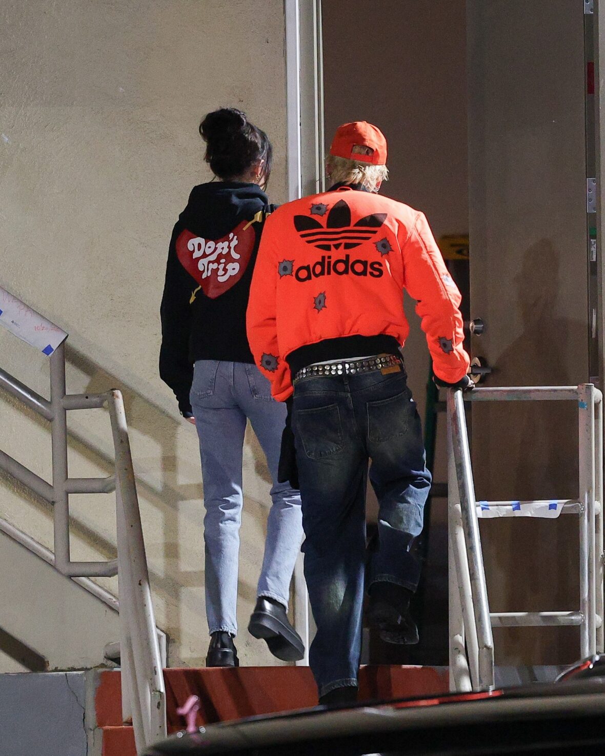 Dakota Johnson and Machine Gun Kelly seen at the studio on October 27, 2027 in Los Angeles, with their backs to the camera walking up the stairs