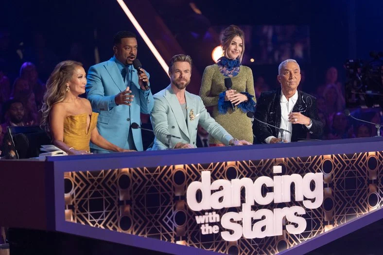 DWTS judges and hosts stand behind the judges desk