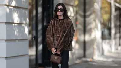 BERLIN, GERMANY - OCTOBER 5: Leo Eberlin spotted wearing Tom Ford over black sunglasses with dark lenses, Manzoni 24 chocolate brown shearling jacket with relaxed box silhouette and tonal button tie, black crew neck top, Leo Mathild diamond jewelry including stud earrings and statement rings, Audemars Piguet gold watches with yellow brown hand structure CC Hardware, black flared trousers by Sézane with a clean high-waisted silhouette, black patent leather heels Tom Ford on October 5, 2026 in Berlin, Germany. (Photo by Jeremy Moeller/Getty Images)