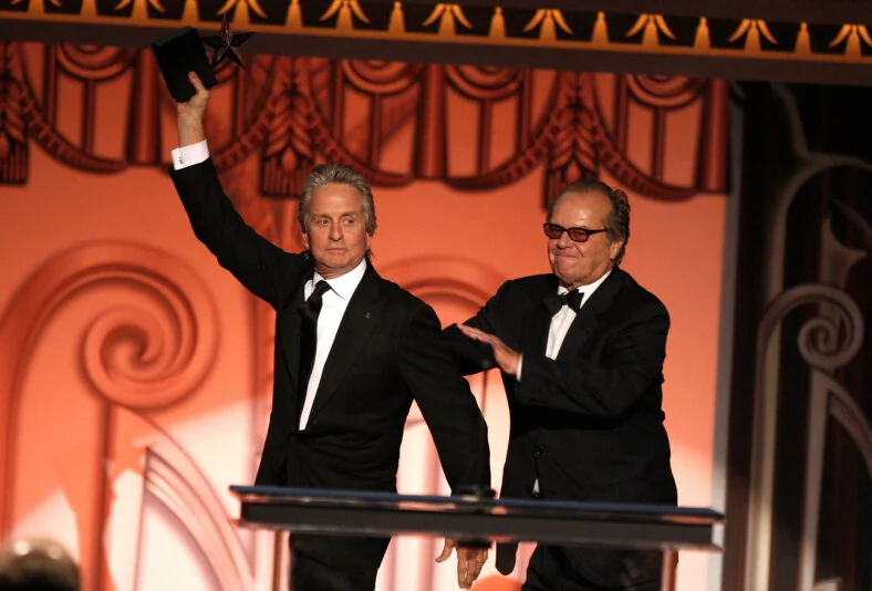 Michael Douglas and Jack Nicholson in suits on stage.
