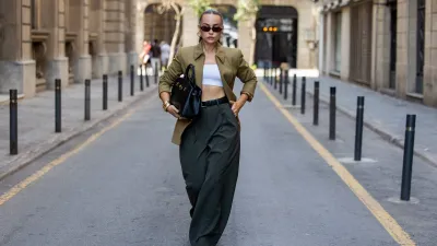 BARCELONA, SPAIN - AUGUST 11: Anna Wein wears Hermes green blazer, Rossi Pants gray wide leg pants, YSL heels, Demellier London black bag, Corlin Eyewear sunglasses on August 11, 2025 in Barcelona, Spain. (Photo by Christian Vierig/Getty Images)